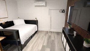 Una habitación de hotel moderna con cama, escritorio, televisor y armario.