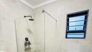 Un baño moderno con ducha de vidrio, inodoro y una ventana pequeña.