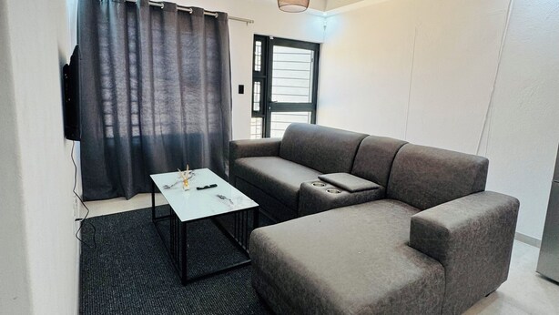 Una sala de estar moderna con un sofá gris, una mesa de centro blanca y una lámpara colgante.