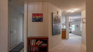 Ein Flur mit Bücherregal, zwei Bildern und einer Tür.