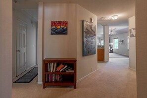 A hallway with a bookshelf, two paintings, and a door. - Family‑Friendly 4BR Getaway Near Alamo Ranch & SeaWorld (San Antonio)