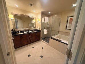 Un baño moderno con tocador de doble lavabo, ducha con cerramiento de vidrio y un espejo grande.
