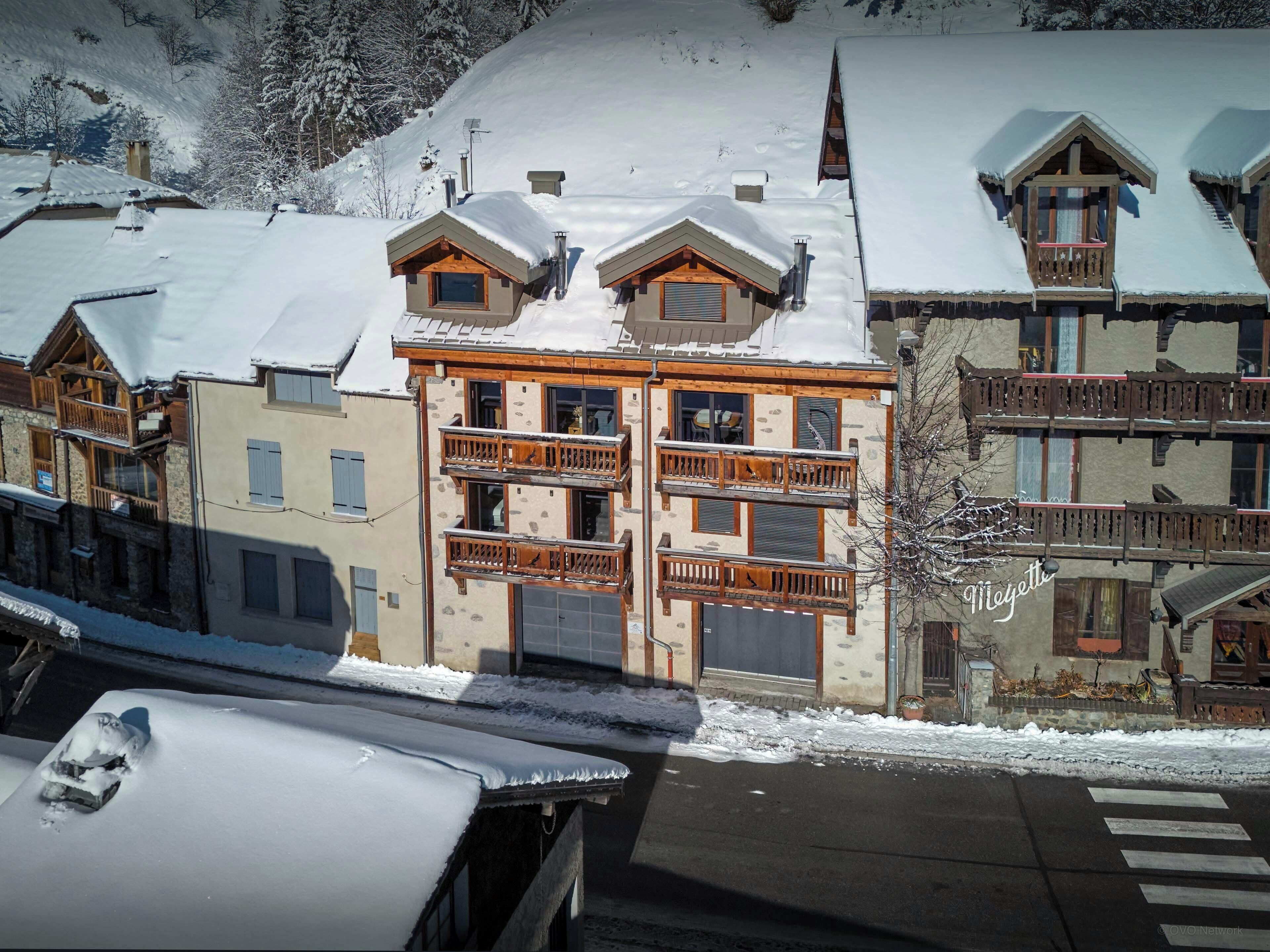 A multi-story building with balconies and a ski slope in the background.
