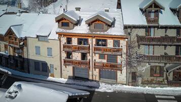 A multi-story building with balconies and a ski slope in the background.