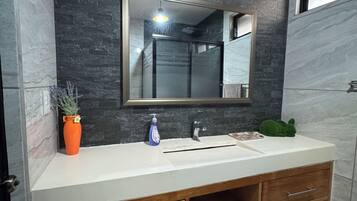 A bathroom with a modern vanity, a large mirror, and a potted plant.