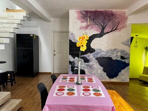 A dining area with a checkered tablecloth, a vase with flowers, and a wall mural.