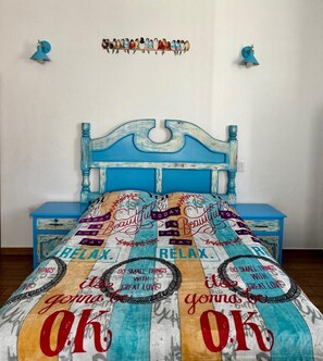Un lit avec une tête de lit bleue et une couvre-lit colorée ornée de phrases motivantes.