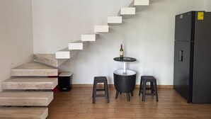 A kitchen with a built-in wooden staircase, a small round table with stools, and a refrigerator. - Casa Terraza Oaxaca (Oaxaca de Juárez)