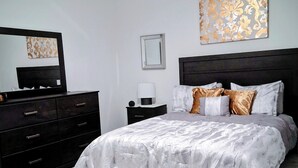 Un dormitorio con cama, cómoda, mesita de noche, lámpara y ventilador de techo.