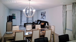 Un comedor con una araña, un sofá y un televisor al fondo.