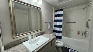 A bathroom with a large mirror, a sink, a toilet, and a shower. - Chic Apt in The Woodlands-Parking-WI-FI-King Bed (Conroe)