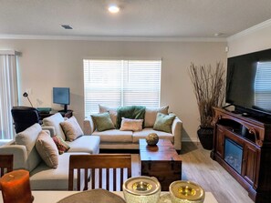 Ein Wohnzimmer mit einer Couch, einem Couchtisch und einem Fernseher.