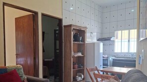 A living room with a sofa, a wooden cabinet, and a dining area with a table and chairs. - Tabalipa House. (Paraty)