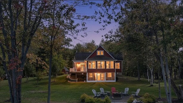 A two-story house with a balcony, surrounded by trees and a grassy yard. - Stunning Lakefront Retreat set on a Private point on North Pond, 9 acres w/beach (Smithfield)