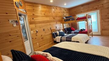 A cozy cabin-style room with wooden walls, a bunk bed, and a door with an American flag.