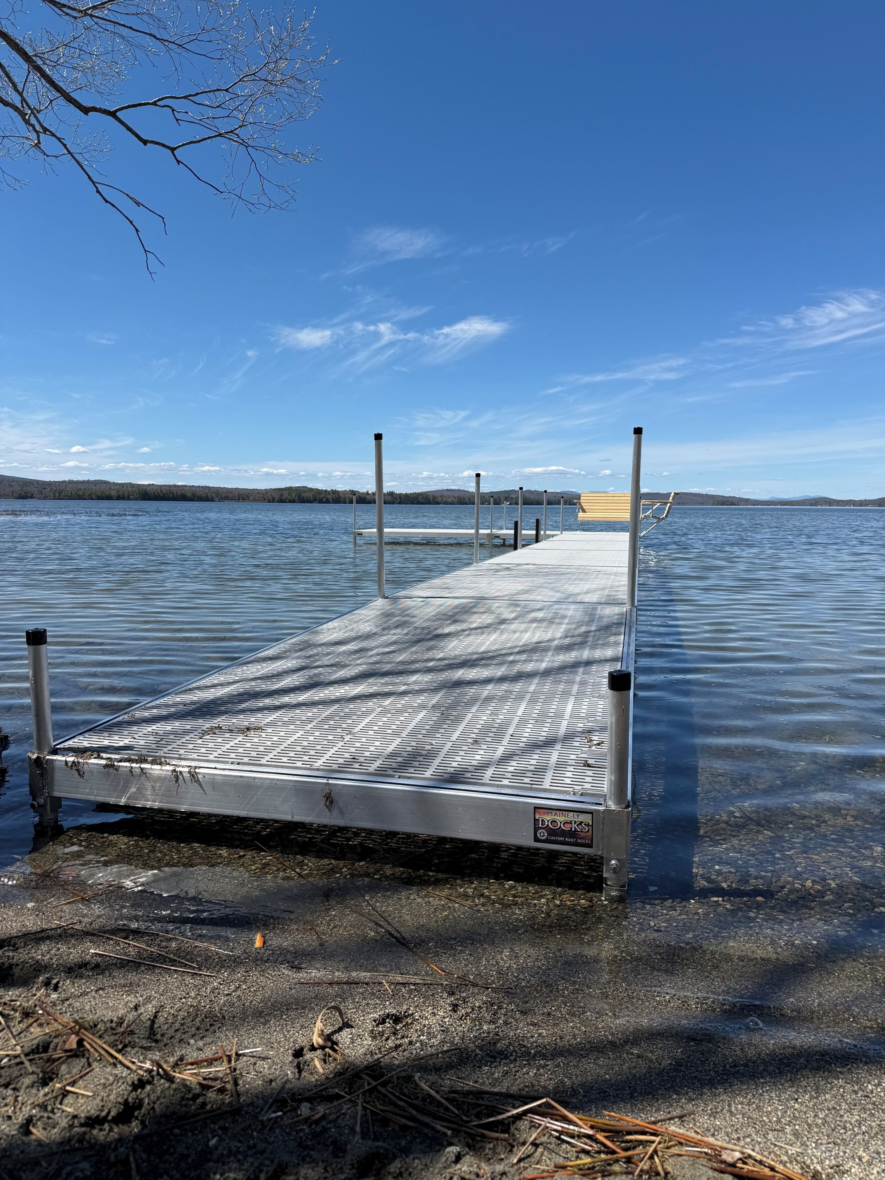 Ein Steg, der sich in einen ruhigen See erstreckt, mit klarem Himmel.