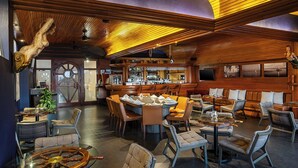 A bar area with wooden decor, a round table, and seating arrangements. - El Cid Marina Beach Hotel - All Inclusive (Mazatlán)
