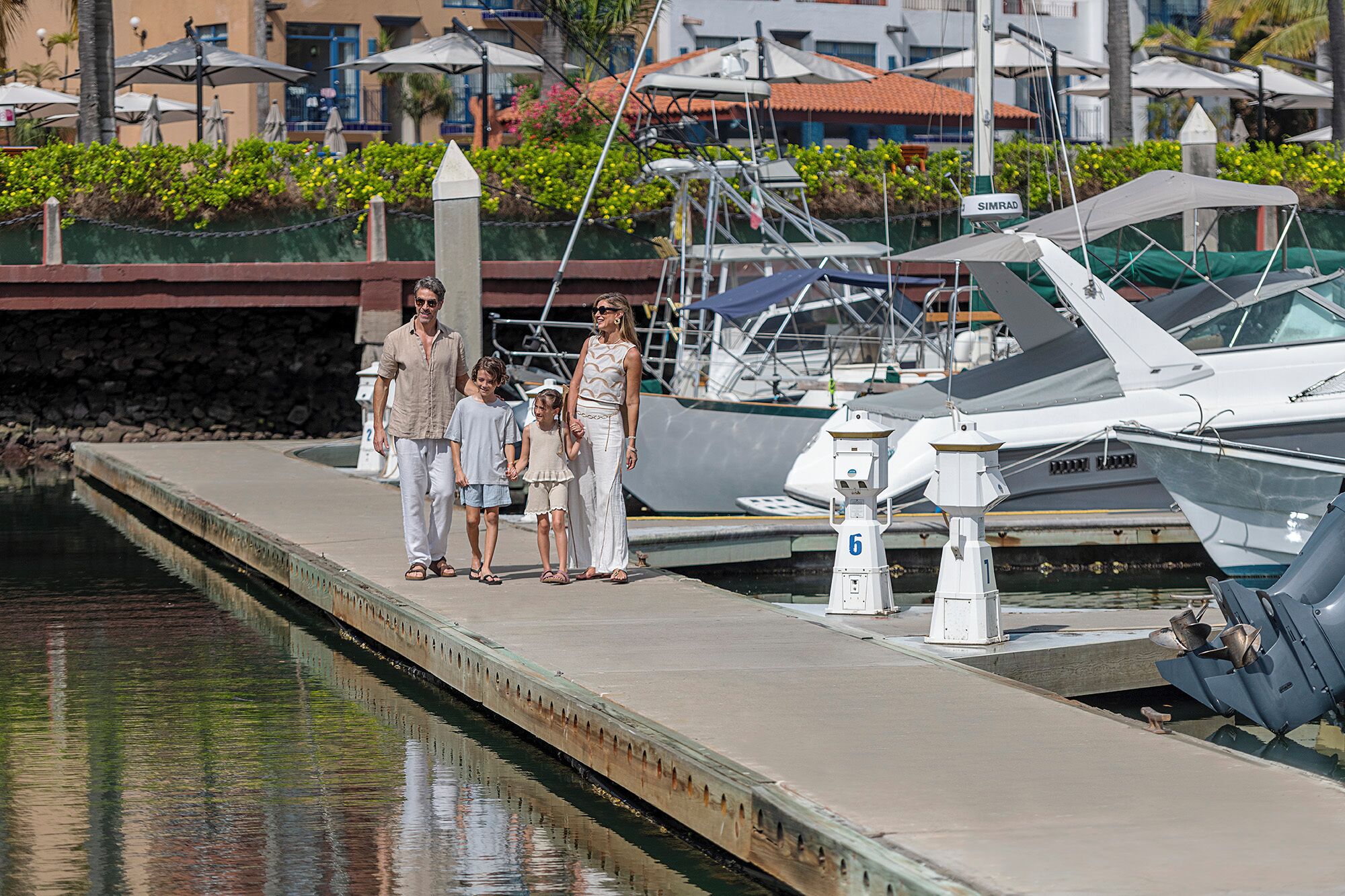 A marina with boats docked, a concrete dock, and a stone wall in the background.