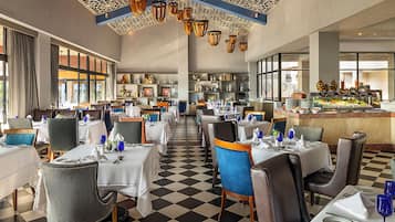A restaurant with checkered flooring, multiple tables with chairs, and a buffet area.