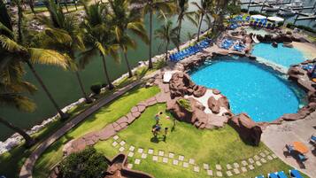 A resort with a large pool, palm trees, and a marina.