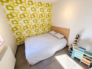 Quarto com cama, penteadeira, radiador e parede estampada.