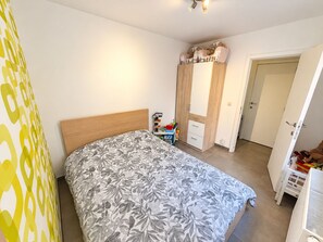 A bedroom with a bed, a wardrobe, a nightstand, and a mirror. - Familytime (Oostende)