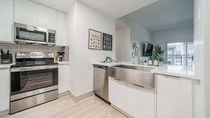 A modern kitchen with stainless steel appliances, white cabinetry, and a dishwasher. - 4BR with Balcony and City View + Parking (Charlotte)