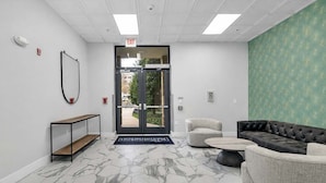 A lobby with a marble floor, a reception desk, a sofa, and a green patterned wall. - Uptown 4 Bed w Balcony Downtown, Parking (Charlotte)