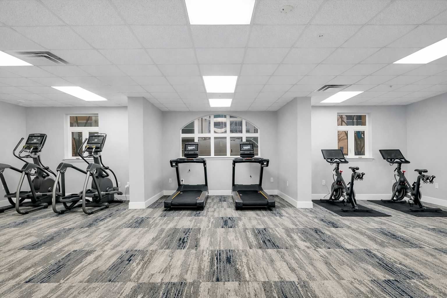 Une salle de sport équipée de tapis de course, d’appareils elliptiques et de vélos d’appartement.