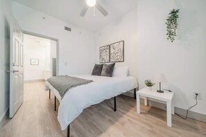 A bedroom with a bed, bedside table, and a ceiling fan. - Uptown Charlotte 3 Bed | City View (Charlotte)