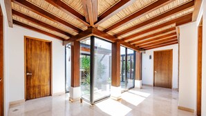 A spacious hallway with wooden beams, large glass doors, and a tiled floor. - Private Pool Luxury Modern House + Free Golf Cart | Llama del Bosque |Reserva Conchal Golf Resort (Cabo Velas)