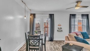 Ein modernes Wohnzimmer mit Essbereich, einer Couch und einem Deckenventilator.