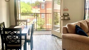 Ein Zimmer mit Balkon, einem Esstisch mit Stühlen und einer Couch.