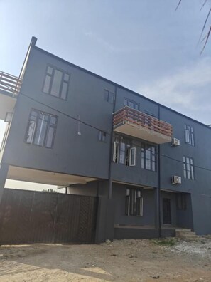 A modern two-story building with a flat roof, large windows, and a balcony with a wooden railing. - STUDIO APT. APARTMENTS (Prampram)
