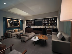 A modern living room with a sofa, coffee table, and a bar area with shelves of bottles.