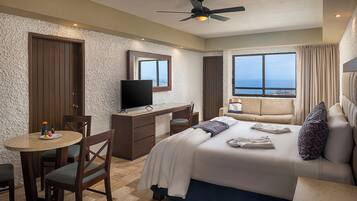 Una habitación de hotel con cama, escritorio, televisor, ventana con vistas y ventilador de techo.