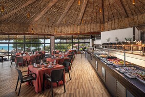 Un restaurant doté d’un toit de chaume, de planchers en bois et de tables dressées pour le service.