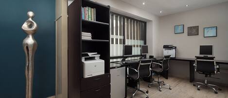 A modern office with a desk, chairs, a printer, and a bookshelf.