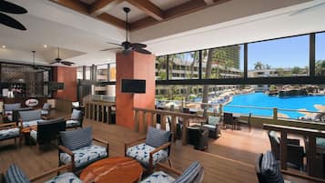 A spacious outdoor lounge area with multiple seating options, a pool view, and a bar area.