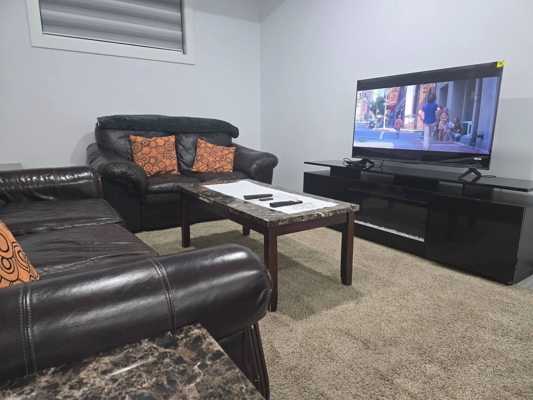A living room with a black leather sofa, a coffee table, and a TV on a black stand.