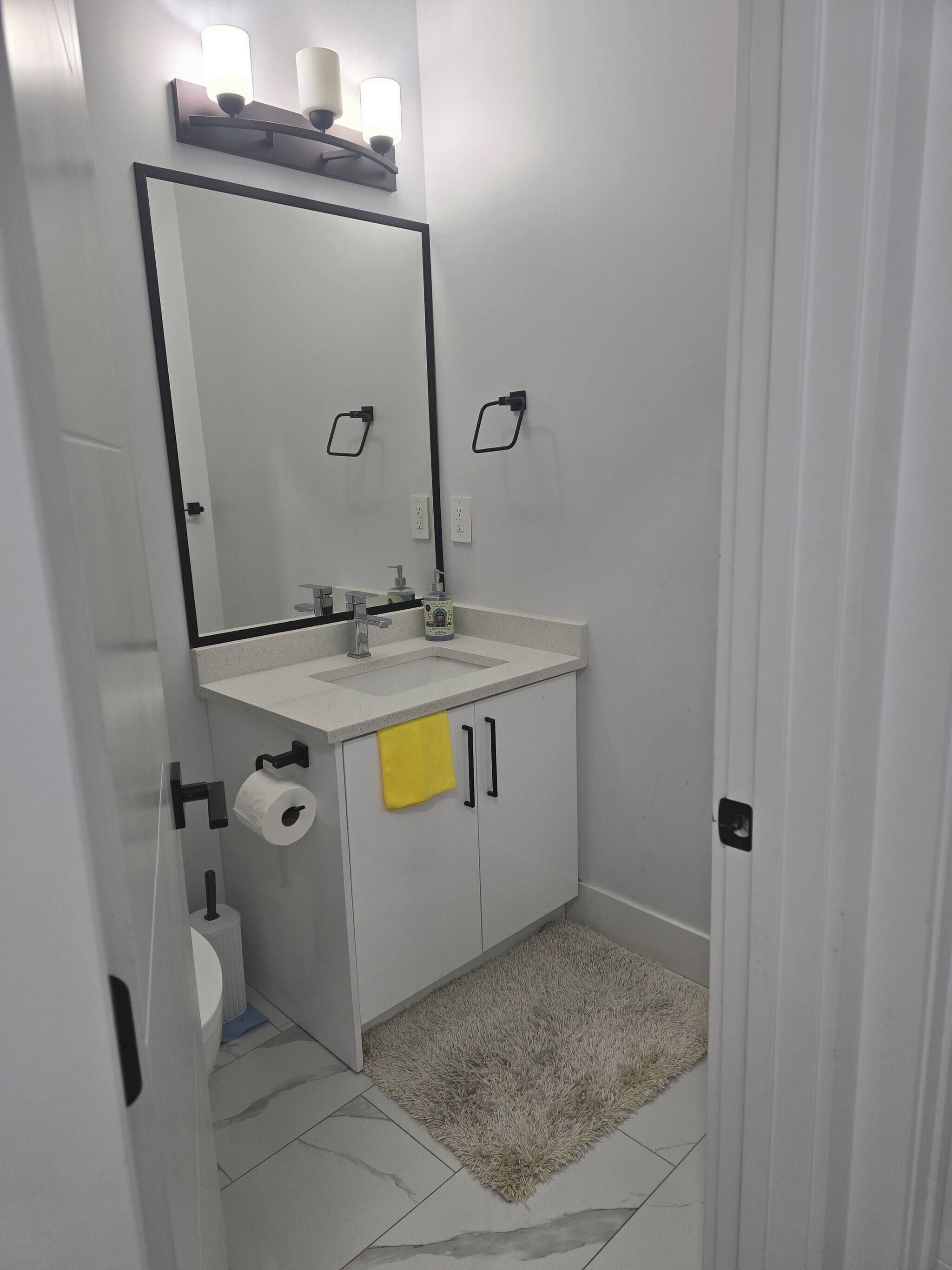A bathroom with a white sink, mirror, and towel rack.