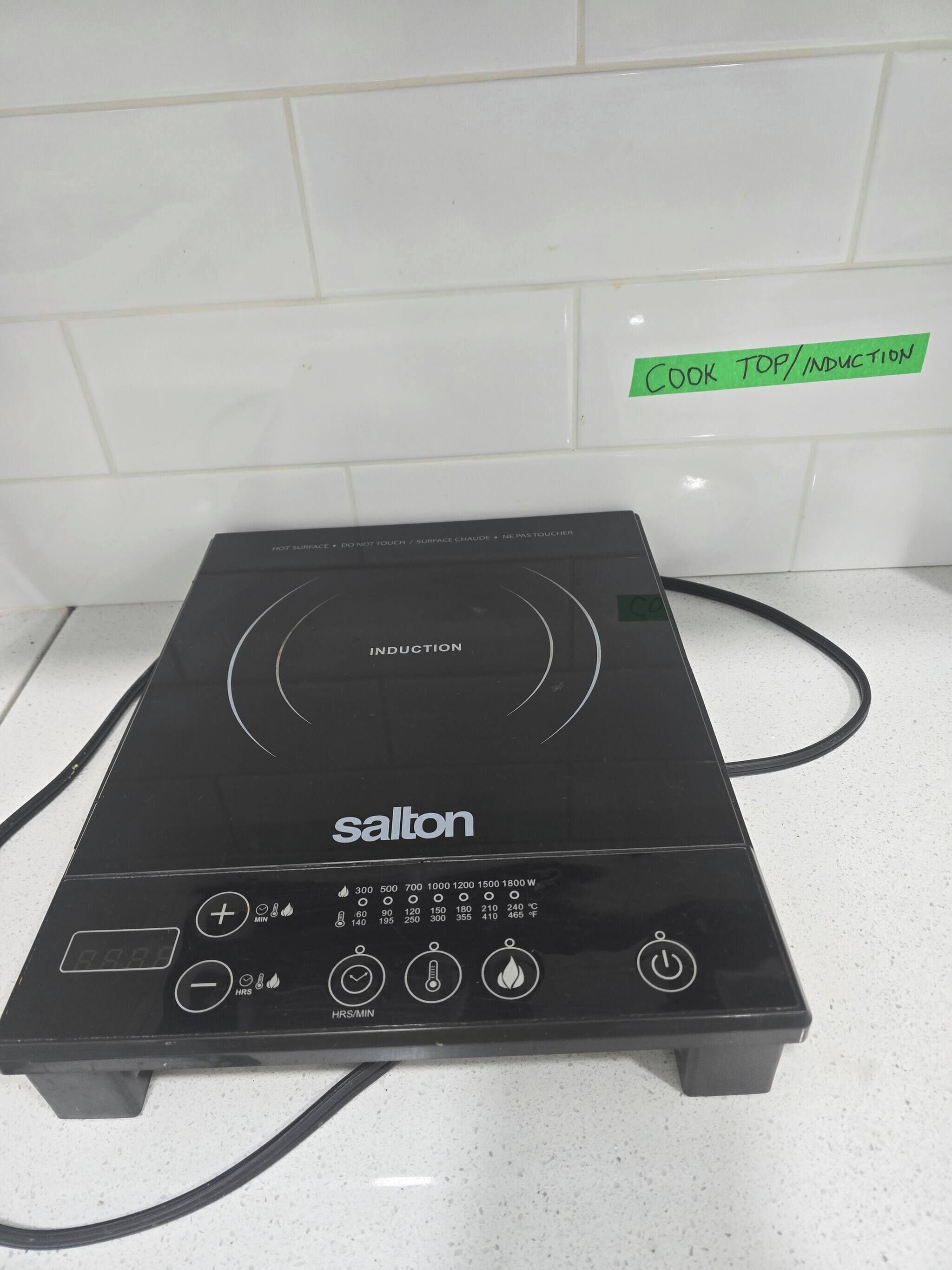 Una cocina de inducción negra con pantalla digital y varios botones de control.