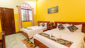 Une chambre d’hôtel avec deux lits, une porte en bois, une fenêtre avec des rideaux, un tableau au mur et un tapis à motifs floraux.