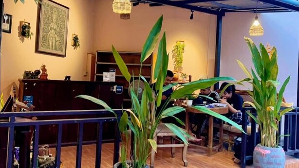 Un espace de détente intérieur avec des tables et des chaises, entouré de plantes en pot.