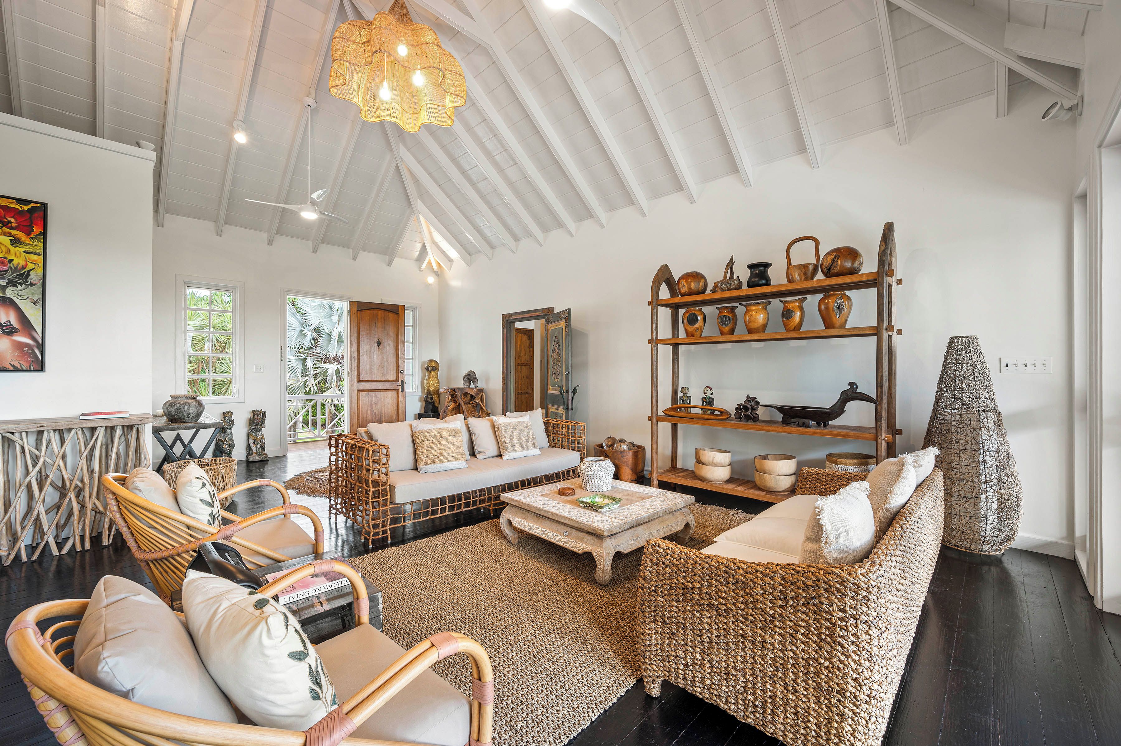 A spacious living area with a high ceiling, wicker furniture, and a variety of decorative items.