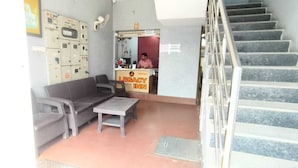 A lobby with a staircase, a reception desk, and a seating area with a sofa and a table. - Stayz Royale Mysuru - Near Mysuru Palace (Mysore)