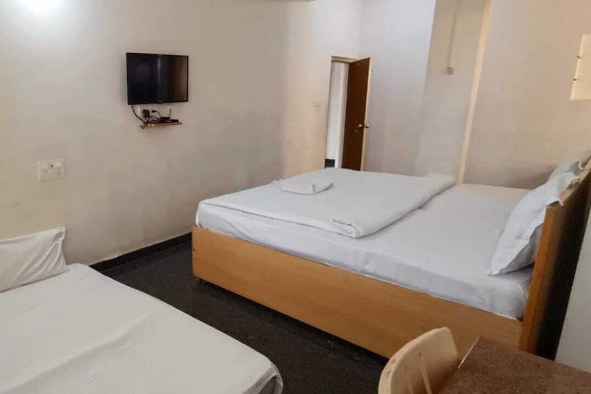 A hotel room with two beds, a TV mounted on the wall, and a door leading to another room.