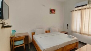 A room with a bed, a desk, a chair, a picture on the wall, and a window with curtains. - Stayz Royale Mysuru - Near Mysuru Palace (Mysore)