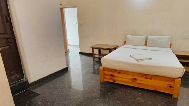 A bedroom with a wooden bed, a small bedside table, and a nightstand. - Stayz Royale Mysuru - Near Mysuru Palace (Mysore)