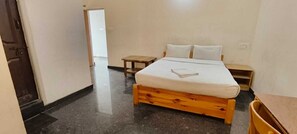 A bedroom with a wooden bed, a small bedside table, and a nightstand. - Stayz Royale Mysuru - Near Mysuru Palace (Mysore)